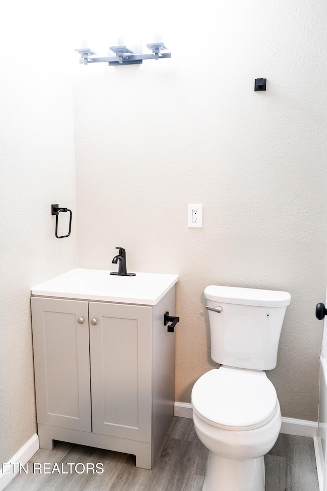 bathroom featuring wood-type flooring, vanity, and toilet