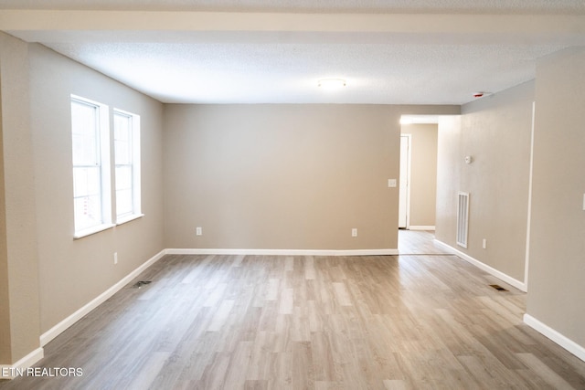 spare room featuring a textured ceiling and light wood-type flooring