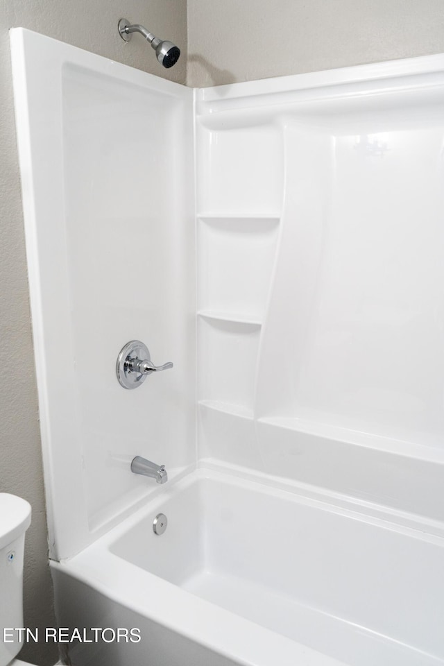 bathroom featuring shower / bathing tub combination and toilet