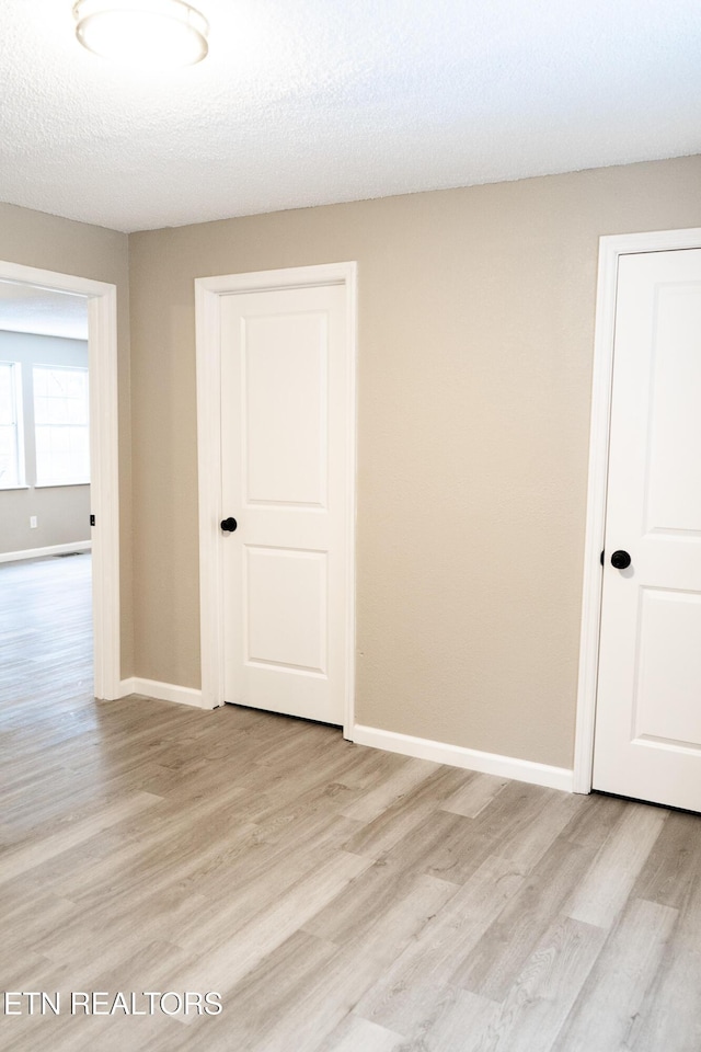 spare room featuring light hardwood / wood-style flooring and a textured ceiling