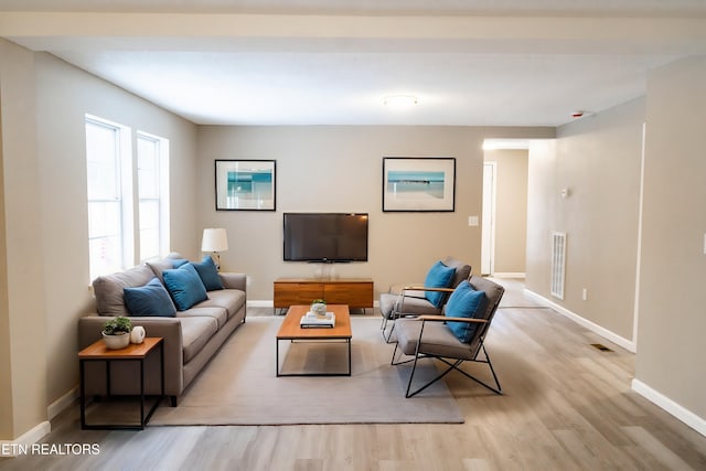 living area featuring wood finished floors, visible vents, and baseboards