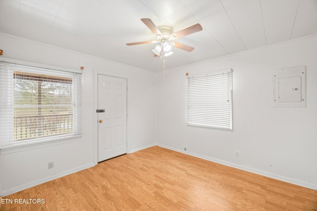 spare room with light wood-type flooring, crown molding, and electric panel