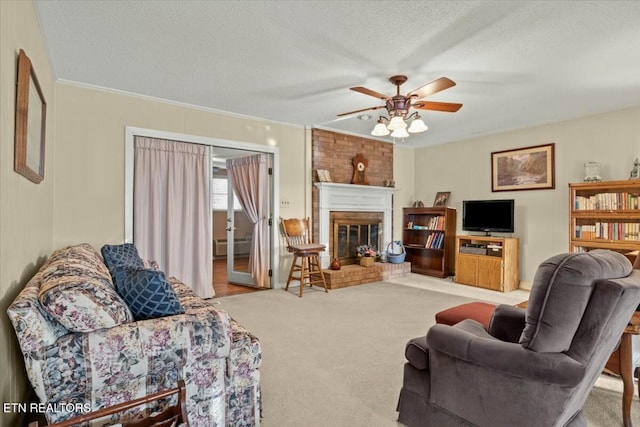 living room with ceiling fan, light colored carpet, a fireplace, crown molding, and a textured ceiling