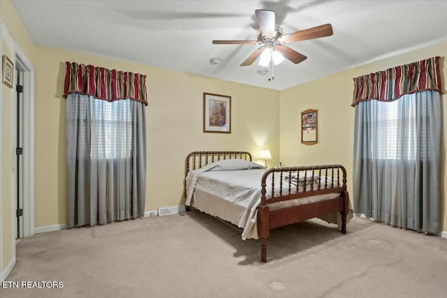 carpeted bedroom with ceiling fan and a textured ceiling