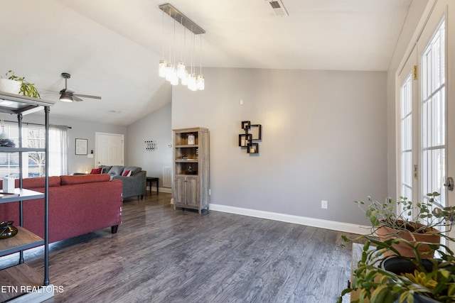 living room with ceiling fan with notable chandelier, dark hardwood / wood-style flooring, and lofted ceiling