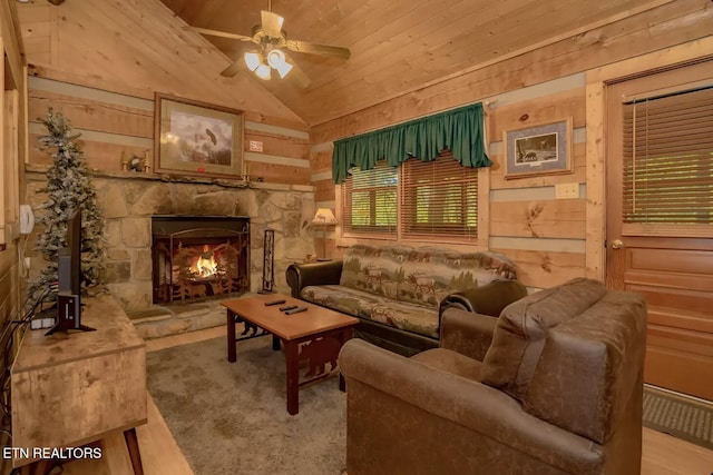 living room featuring high vaulted ceiling, a stone fireplace, wood ceiling, and wooden walls