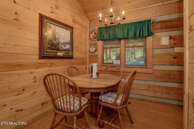 dining room with hardwood / wood-style flooring, a chandelier, wood walls, and vaulted ceiling