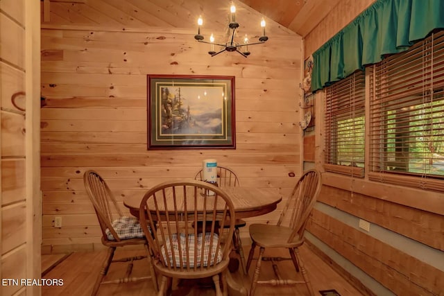 dining area featuring wood walls, an inviting chandelier, wood ceiling, and hardwood / wood-style flooring