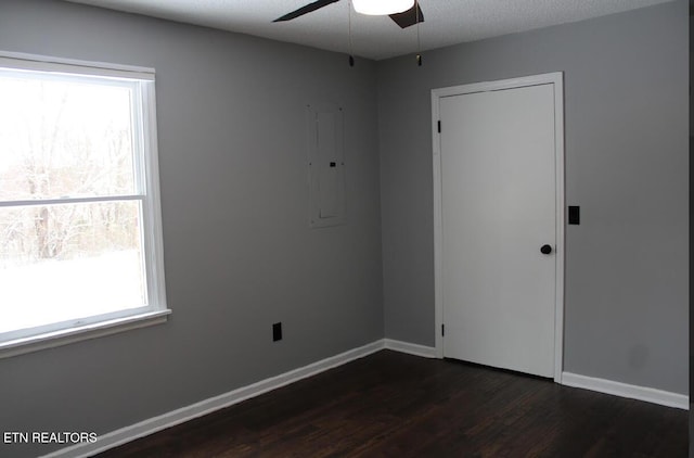 spare room with ceiling fan, dark hardwood / wood-style floors, electric panel, and a textured ceiling