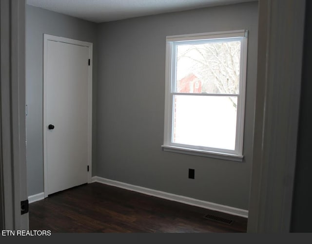 unfurnished room with dark hardwood / wood-style flooring