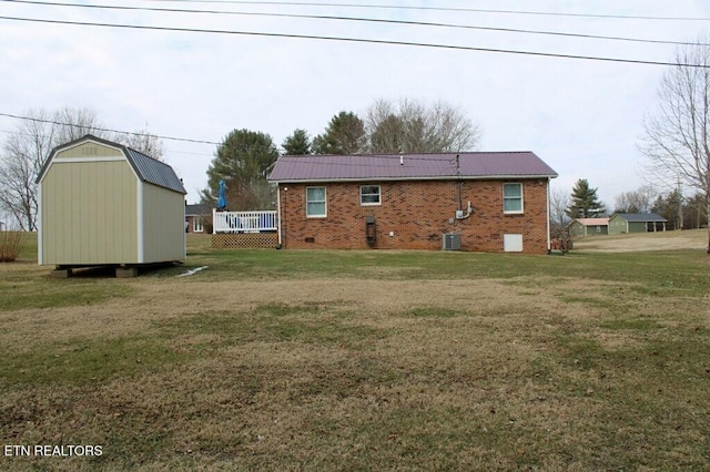 back of house featuring cooling unit, a yard, and a storage unit