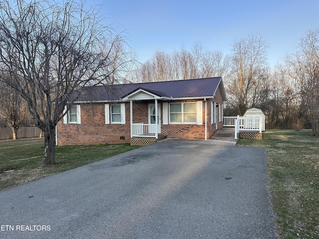 view of front of property with aphalt driveway, brick siding, metal roof, and a front yard