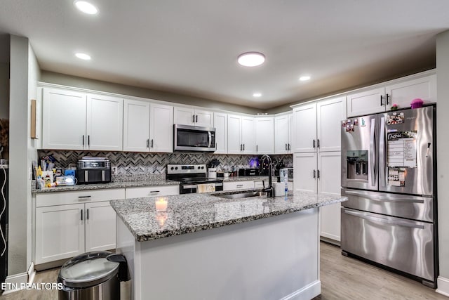 kitchen featuring sink, light wood-type flooring, light stone counters, white cabinetry, and stainless steel appliances