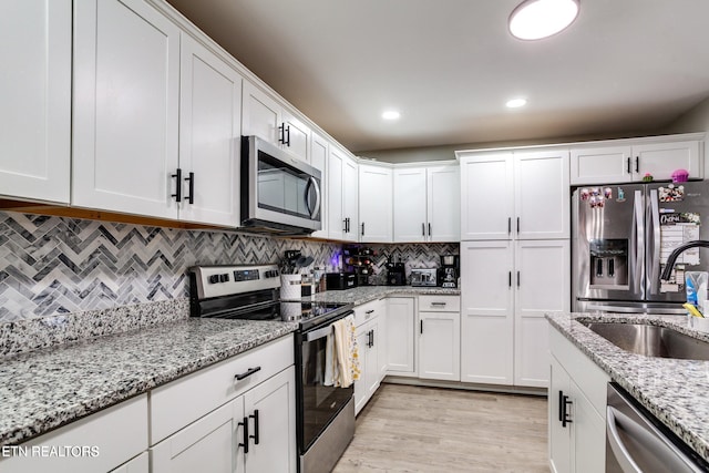 kitchen featuring white cabinetry, sink, tasteful backsplash, light stone counters, and appliances with stainless steel finishes