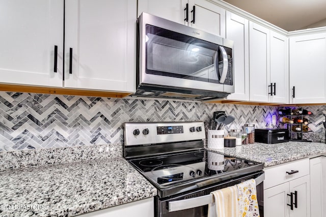 kitchen featuring light stone countertops, white cabinetry, appliances with stainless steel finishes, and tasteful backsplash