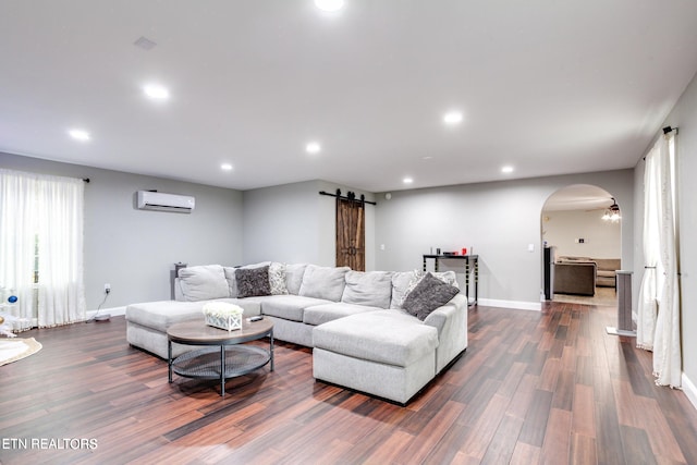 living room featuring an AC wall unit, a barn door, ceiling fan, and dark hardwood / wood-style flooring