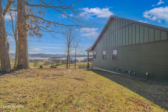 view of side of property with a mountain view and a lawn