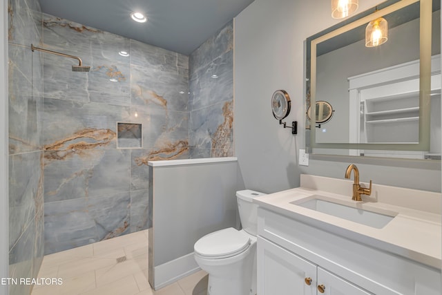 bathroom with a tile shower, tile patterned floors, vanity, and toilet