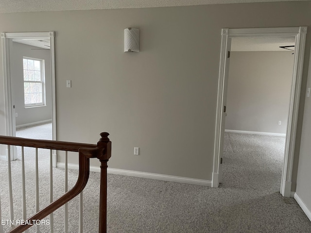 hallway featuring carpet flooring and a textured ceiling