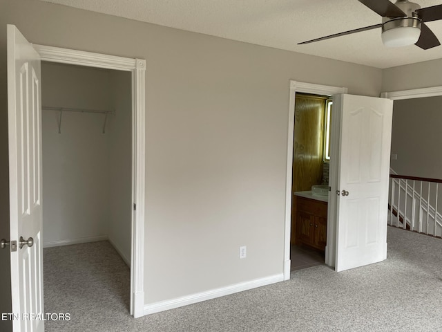 unfurnished bedroom with ceiling fan, carpet floors, a textured ceiling, a walk in closet, and a closet