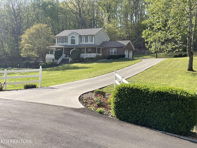colonial house featuring a garage, fence, a front lawn, and driveway