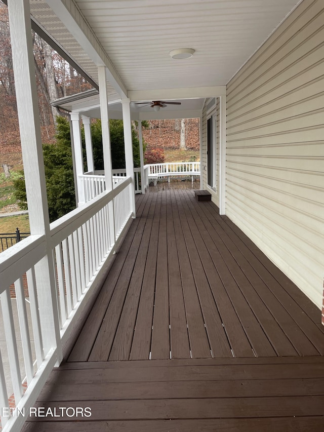 wooden deck featuring covered porch and a ceiling fan