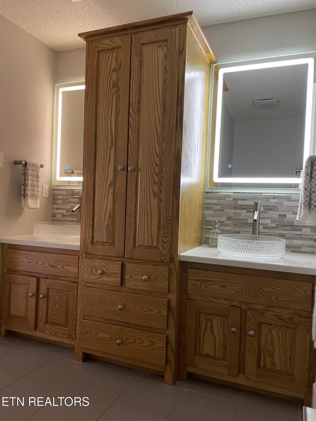 bathroom with vanity, a textured ceiling, tile patterned floors, and tasteful backsplash