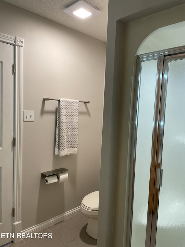 bathroom featuring baseboards, toilet, and tile patterned flooring