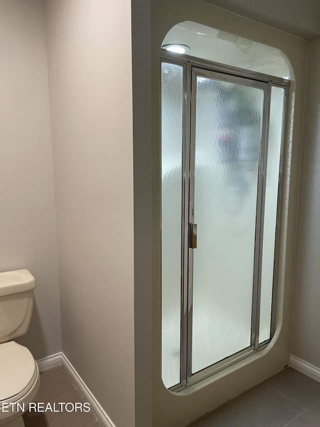full bath with tile patterned floors, baseboards, a shower stall, and toilet