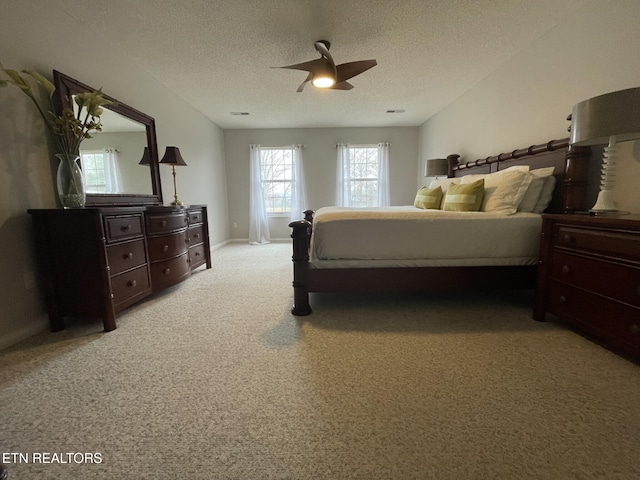 carpeted bedroom with a textured ceiling, ceiling fan, visible vents, and baseboards