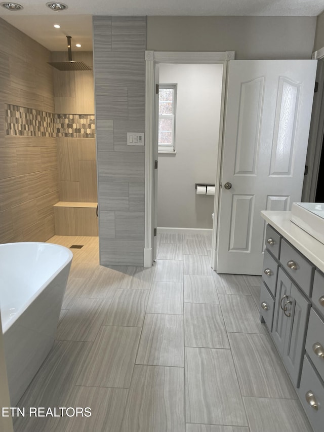 bathroom with walk in shower, vanity, a soaking tub, and baseboards