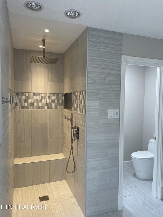 bathroom featuring tile patterned floors, recessed lighting, toilet, and a tile shower