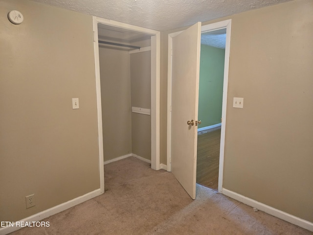 hallway with a textured ceiling and light carpet