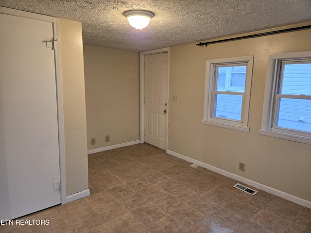 unfurnished room featuring a textured ceiling