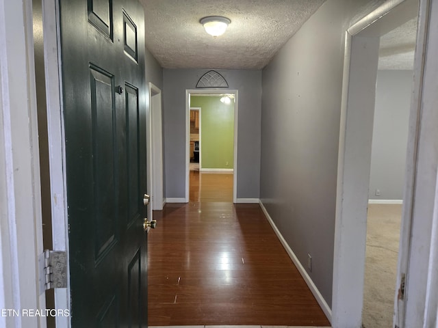 hallway featuring a textured ceiling and dark hardwood / wood-style floors