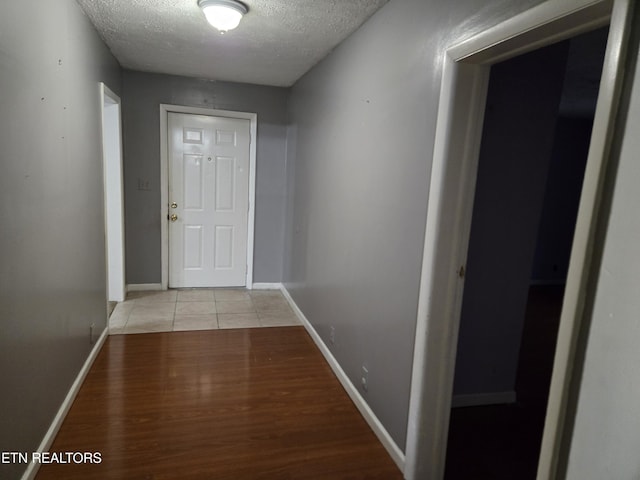 hall featuring light hardwood / wood-style floors and a textured ceiling