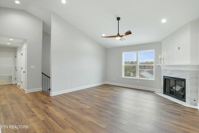 unfurnished living room featuring hardwood / wood-style flooring, vaulted ceiling, a premium fireplace, and ceiling fan