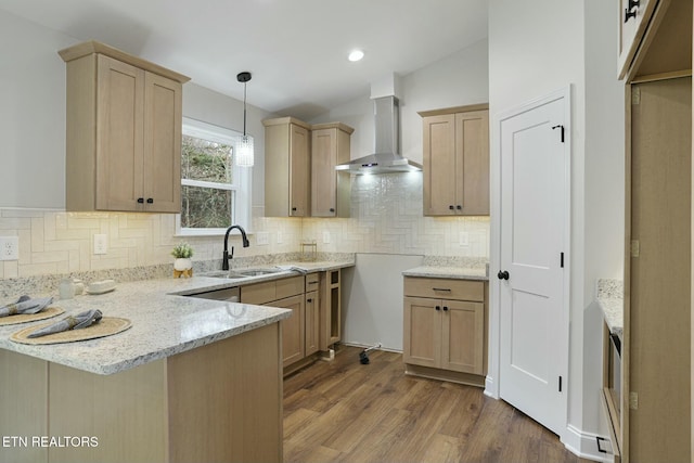 kitchen with sink, wall chimney range hood, and light brown cabinetry