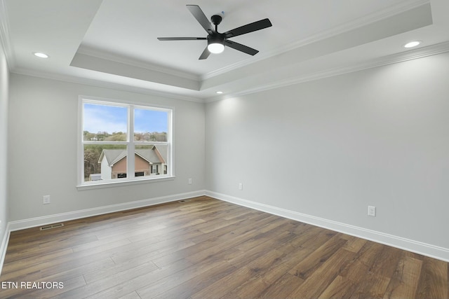 spare room with hardwood / wood-style floors, crown molding, and a raised ceiling