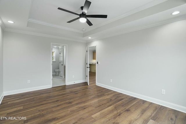 spare room featuring a tray ceiling, ornamental molding, dark hardwood / wood-style floors, and ceiling fan