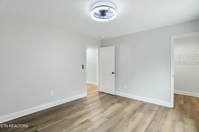 unfurnished bedroom with a spacious closet, light hardwood / wood-style flooring, and a closet