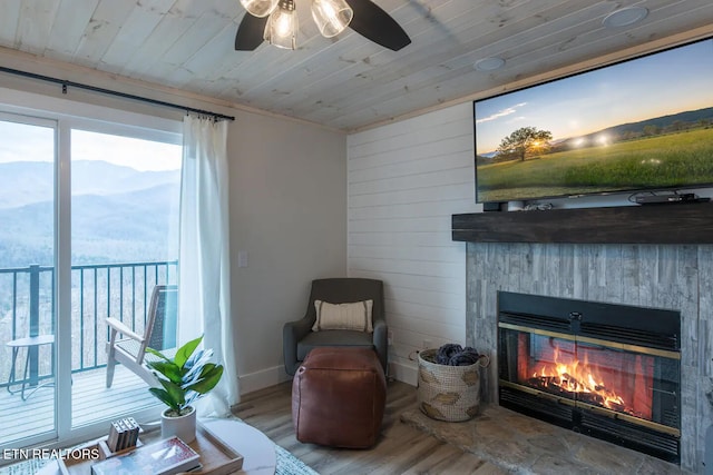 living area featuring wood walls, a stone fireplace, wood-type flooring, and wood ceiling