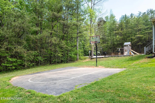 view of basketball court with a lawn and a playground