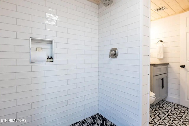 bathroom with tiled shower, vanity, and toilet