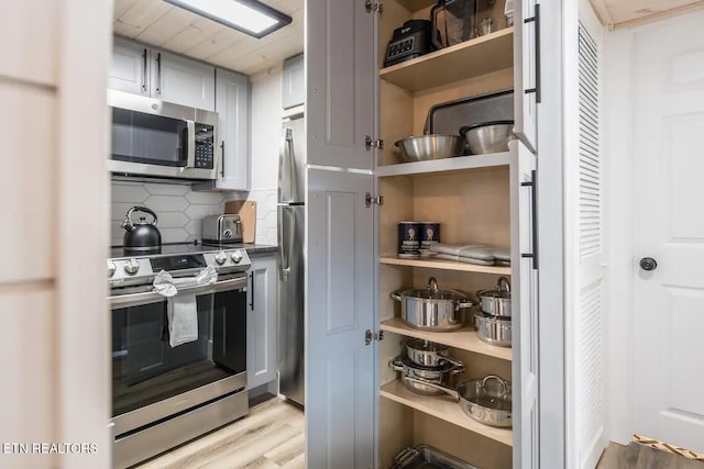 kitchen featuring decorative backsplash, gray cabinets, stainless steel appliances, and light hardwood / wood-style flooring