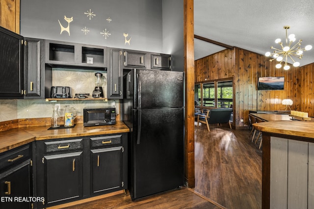 kitchen with dark hardwood / wood-style flooring, black appliances, pendant lighting, a notable chandelier, and butcher block counters