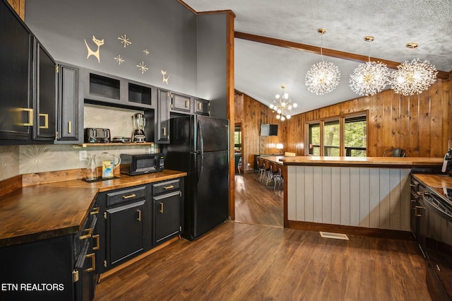 kitchen featuring butcher block counters, hanging light fixtures, a notable chandelier, lofted ceiling, and black appliances