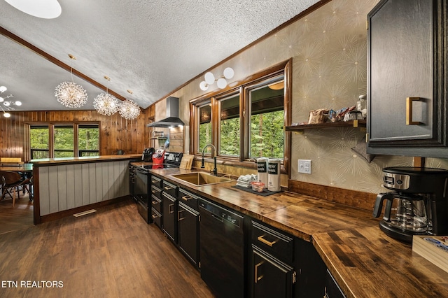 kitchen with wooden counters, black appliances, sink, hanging light fixtures, and wall chimney exhaust hood