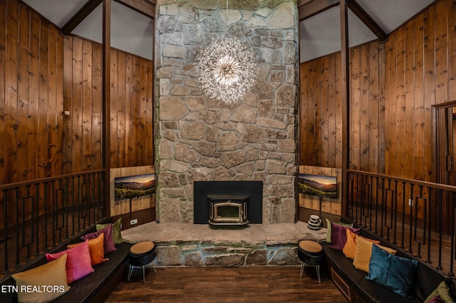 living room with wood-type flooring, lofted ceiling with beams, a wood stove, and wood walls