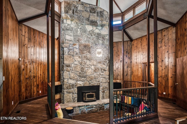 living room with a wood stove, wooden walls, and lofted ceiling with beams